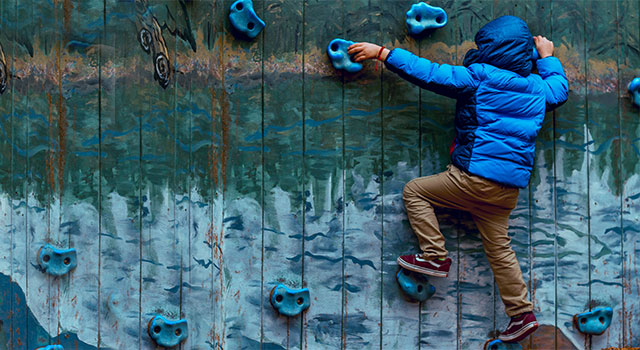child scaling a climbing wall